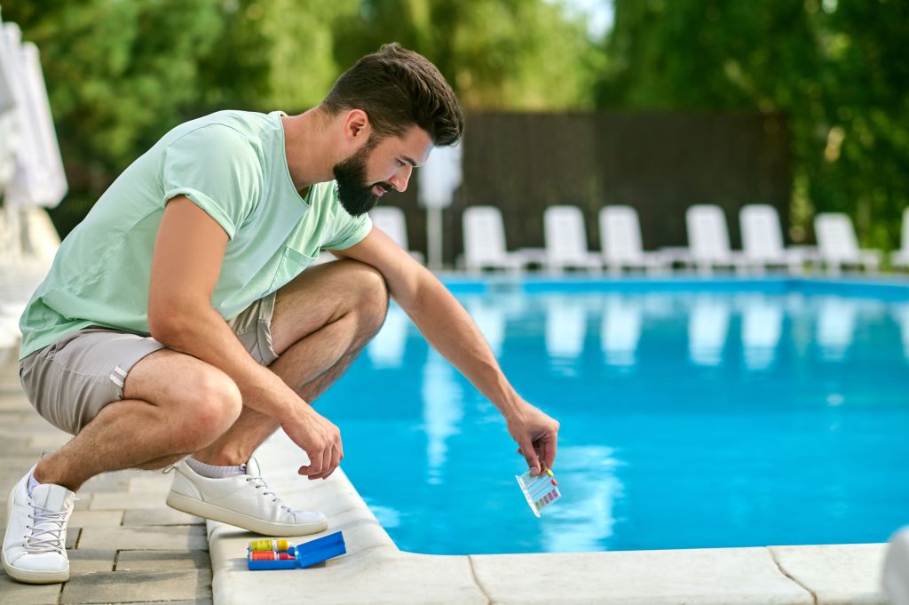 A service man making a water test in a swimming pool
